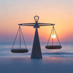 Metal scales with stone pans perfectly balanced against a coastal sunset background.